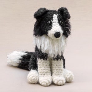 May include: A crocheted black and white border collie dog toy. The dog is sitting with its paws in front of it. The dog has a fluffy white tail.