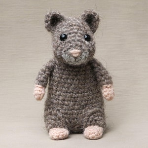 May include: A small, gray crocheted mouse toy with pink paws and black eyes.