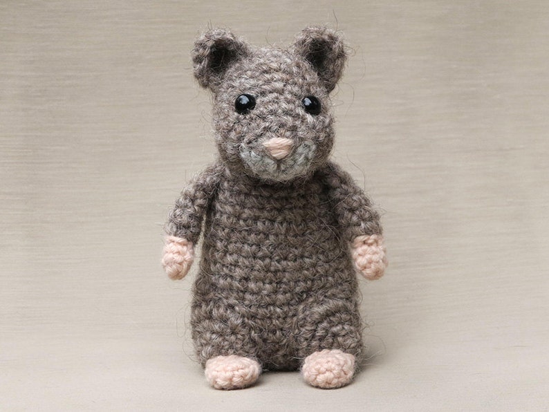 May include: A small, gray crocheted mouse toy with pink paws and black eyes.