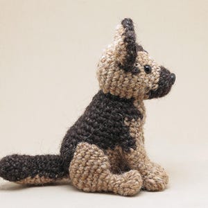 K&ouml;nnte beinhalten: Ein geh&auml;keltes Stofftier in Form eines Deutschen Sch&auml;ferhundes. Der Hund ist braun und beige mit schwarzem Fell. Der Hund sitzt mit dem Kopf zur Seite gedreht.