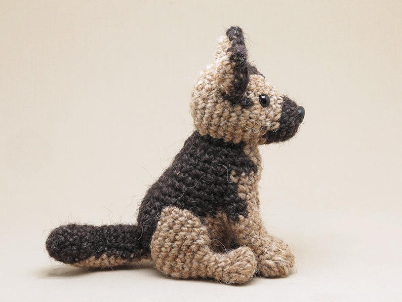K&ouml;nnte beinhalten: Ein geh&auml;keltes Stofftier in Form eines Deutschen Sch&auml;ferhundes. Der Hund ist braun und beige mit schwarzem Fell. Der Hund sitzt mit dem Kopf zur Seite gedreht.