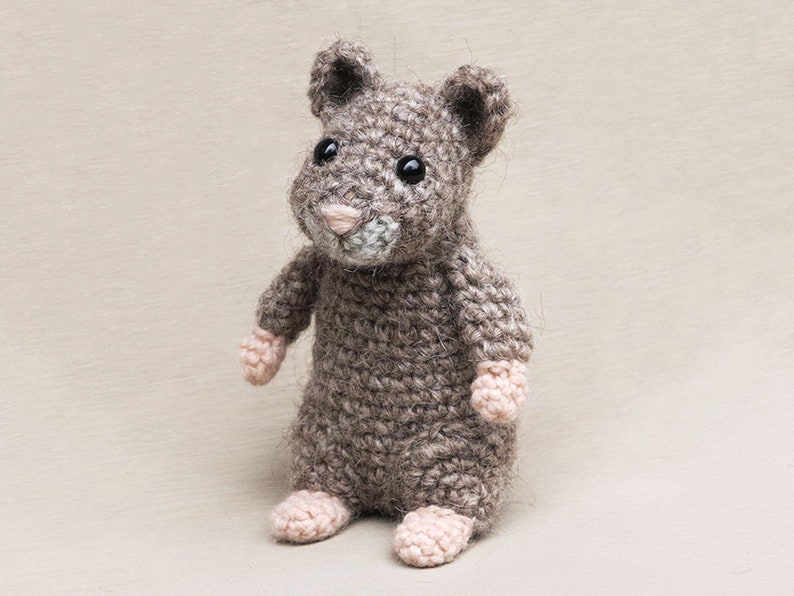May include: A crocheted gray hamster toy with pink feet and black eyes.