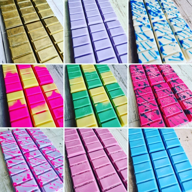 May include: Assortment of wax melts in various colors and patterns. The wax melts are arranged in rows of six, with each row featuring a different color and pattern. The colors include gold, purple, green, pink, blue, and white. The patterns include solid colors, stripes, and splatters.