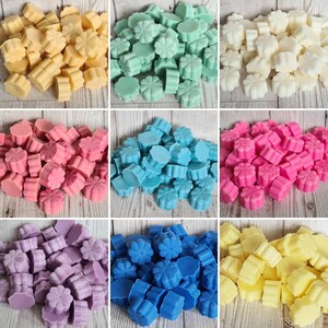 Pode incluir: Conjunto de ceras derretidas em v&aacute;rias cores e formas, incluindo amarelo, azul, rosa, roxo e verde. As ceras derretidas est&atilde;o dispostas em um padr&atilde;o de grade em uma superf&iacute;cie de madeira.