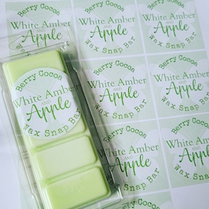 May include: A close-up of a green and white wax melt snap bar with the label "Berry Cocoa White Amber and Apple Wax Snap Bar".