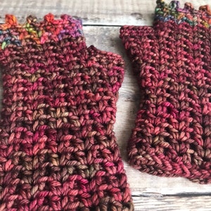May include: A pair of fingerless gloves in a deep burgundy color with a multi-colored yarn detail at the top.