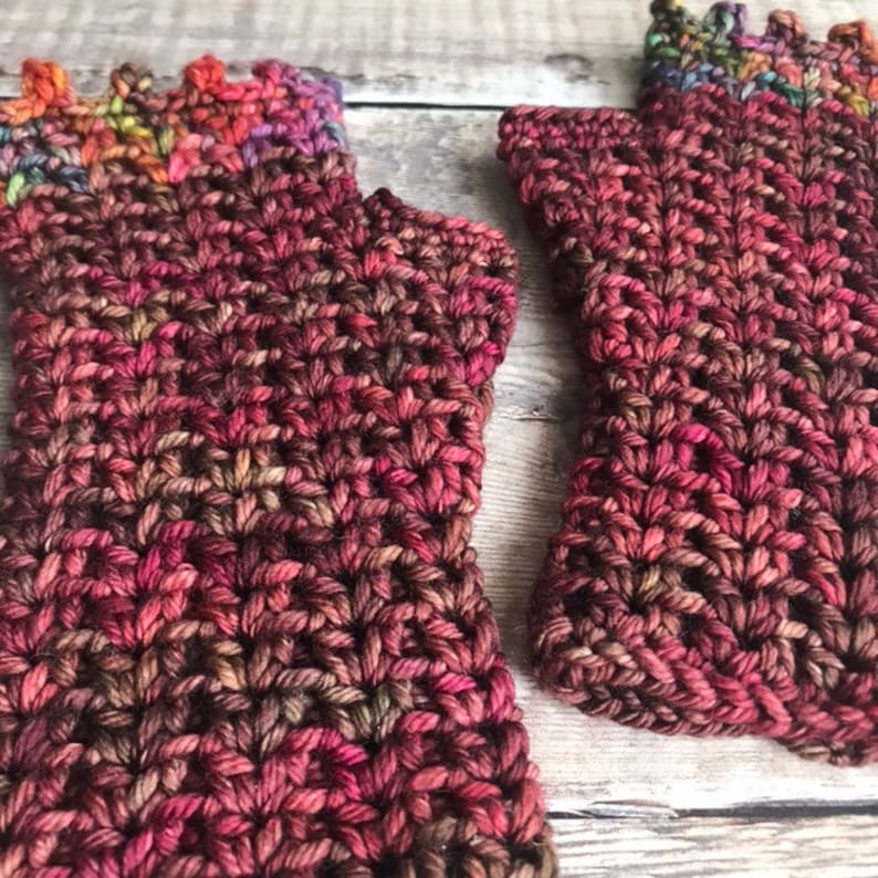 May include: A pair of fingerless gloves in a deep burgundy color with a multi-colored yarn detail at the top.