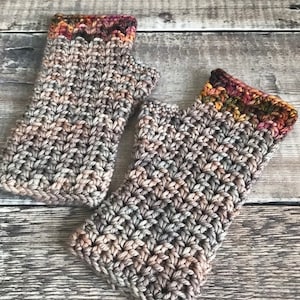 May include: A pair of crocheted fingerless gloves with a brown, gray, and orange color scheme. The gloves have a textured stitch pattern and a colorful band at the top.
