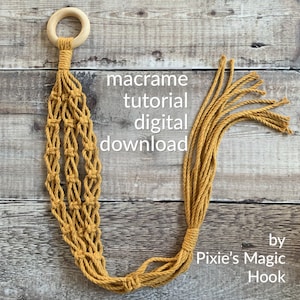 Pode incluir: Um tutorial de download digital para um suporte de plantas de macramé, com um cordão amarelo mostarda e um anel de madeira. O texto "macrame tutorial digital download" e "by Pixie's Magic Hook" é visível na imagem.