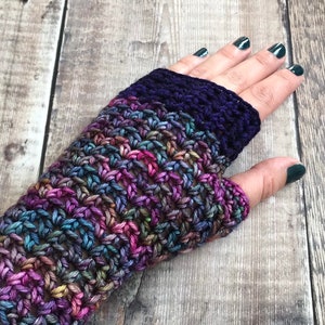 May include: Crocheted fingerless gloves in a multi-colored yarn with a purple band at the wrist.