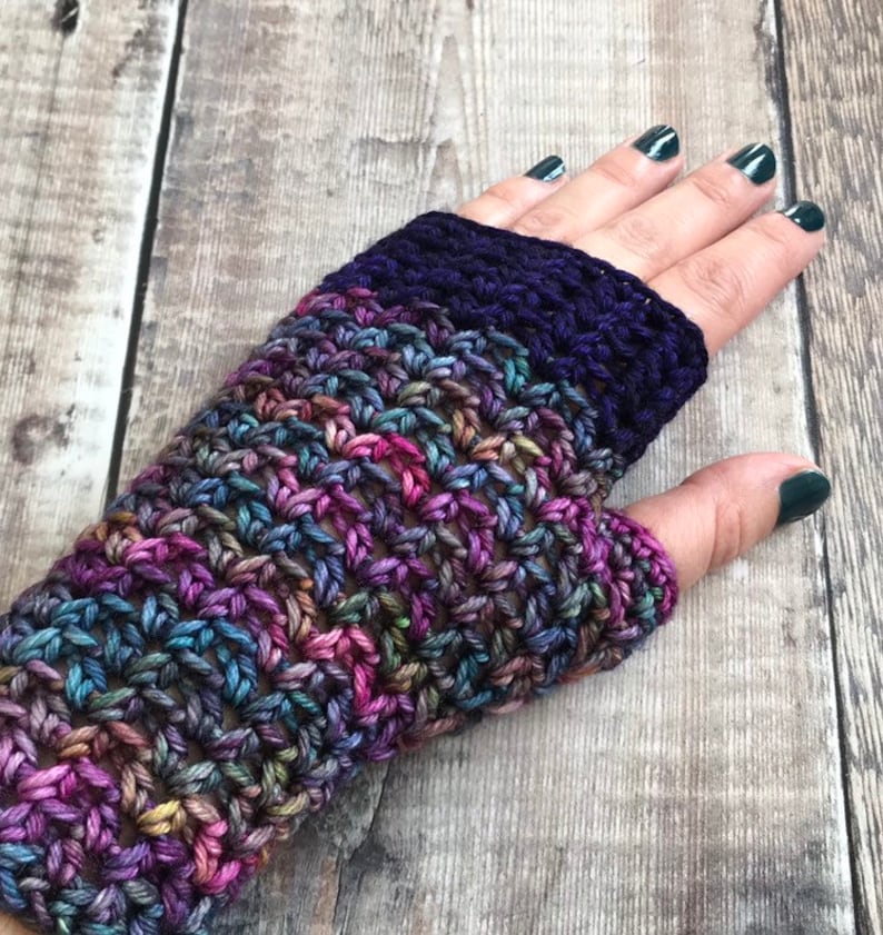 May include: Crocheted fingerless gloves in a multi-colored yarn with a purple band at the wrist.