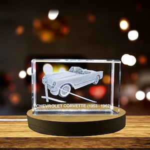 Może przedstawiać: Przezroczysty kryształowy sześcian z trójwymiarowym laserowym grawerem obrazu klasycznego Chevroleta Corvette. Pod samochodem wygrawerowano tekst "CHEVROLET CORVETTE (1953 - 1962)".