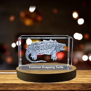 May include: A clear glass cube with a 3D etched image of a common snapping turtle. The cube is on a wooden base and the text "Common Snapping Turtle" is printed below the image.