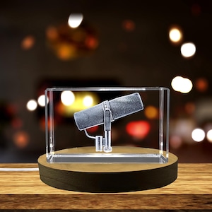 May include: A crystal cube with a 3D laser engraved image of a microphone on a wooden base.