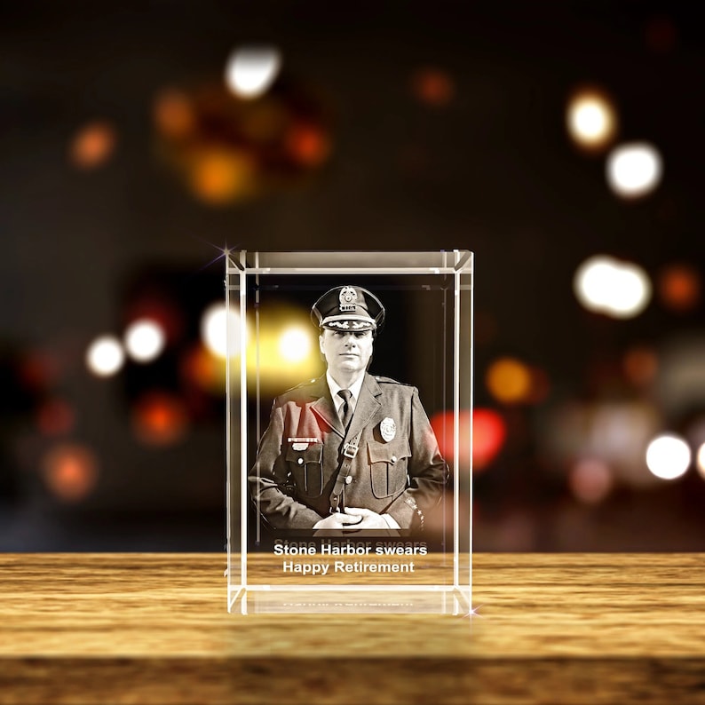 K&ouml;nnte beinhalten: Ein Kristallw&uuml;rfel mit einem 3D-Bild eines Polizisten in Uniform. Der Text "Stone Harbor swears Happy Retirement" ist auf der Basis des W&uuml;rfels eingraviert.