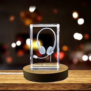 May include: A crystal cube with a 3D etched image of a headset and microphone. The cube is on a wooden base and has the text "Headset Microphone" on the front.