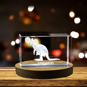 May include: A clear crystal cube with a 3D laser engraved image of a kangaroo with a joey in its pouch. The cube is on a wooden base and the word "KANGAROO" is engraved on the base.