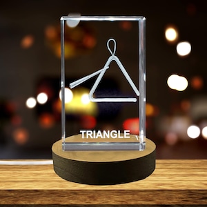 May include: A clear glass cube with a silver triangle and the word "TRIANGLE" engraved on the bottom. The cube is sitting on a wooden base.