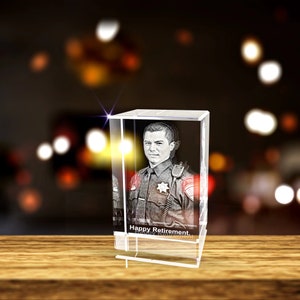 K&ouml;nnte beinhalten: Ein 3D-Kristallw&uuml;rfel mit einem Schwarzwei&szlig;bild eines Polizisten in Uniform. Der Text "Happy Retirement" ist in den Sockel des W&uuml;rfels graviert.