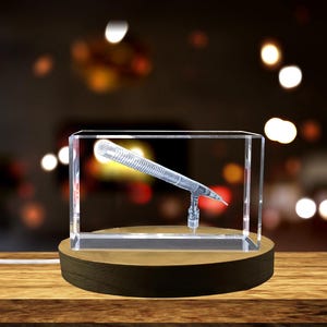 May include: A crystal cube with a 3D laser engraved image of a microphone on a wooden base.