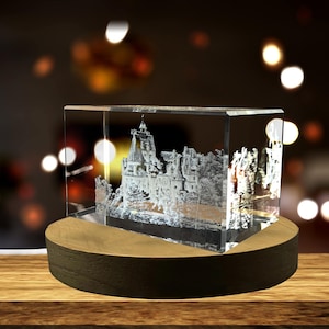 May include: A clear glass cube with a 3D laser engraved image of a castle. The cube is sitting on a wooden base.