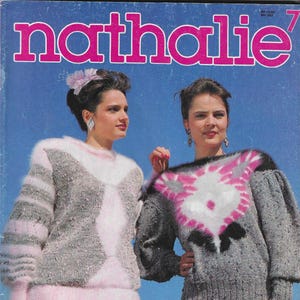 Op de afbeelding: Twee vrouwen dragen roze en grijze truien met een wit en roze ontwerp. De truien zijn pluche en hebben een textuur. De vrouwen dragen roze rokken en broeken. De afbeelding heeft de tekst "nathalie" en "SINGER" erop.
