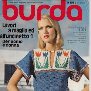 May include: A magazine cover featuring a woman wearing a blue crocheted top with a colorful floral design. The magazine is titled "burda" and the text "Lavori a maglia ed all'uncinetto 1 per uomo e donna" is visible. The magazine cover also includes the text "Nuovi modelli per l'estate e le vacanze".