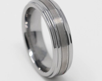 May include: A silver tungsten carbide ring with a grooved design. The ring has a brushed finish and a polished edge.