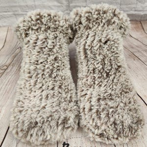 May include: A pair of fluffy brown and white slipper socks. The socks are made from a soft, plush material and have a comfortable fit.