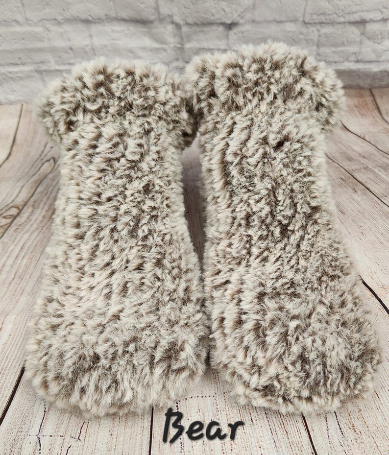 May include: A pair of fluffy brown and white slipper socks. The socks are made from a soft, plush material and have a comfortable fit.