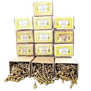 Peut inclure: Une collection de vis en laiton vintage dans leurs boîtes en carton d'origine. Les boîtes sont étiquetées "NETTLEFOLDS" avec "1 SCREWS 6" imprimé dessus. Les vis sont éparpillées autour des boîtes ouvertes.