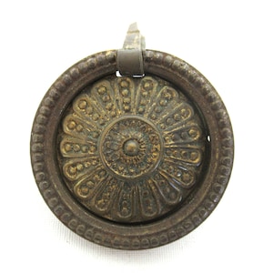 Può includere: Una manopola per porta in ottone vintage con un design floreale decorativo. La manopola ha un anello di trazione e un centro dettagliato.
