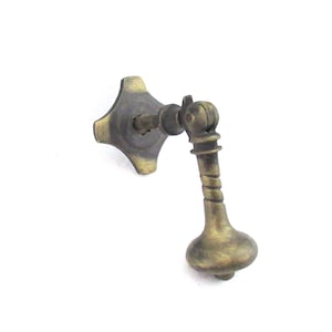May include: Antique brass drawer pull. The starburst-shaped backplate and bulbous handle give it a vintage look. This metal drawer pull is ideal for adding a touch of classic charm to furniture. The handle is approximately 7 cm long.