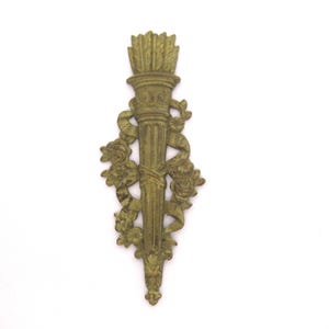 May include: A gold-colored metal wall decor featuring a torch with a floral design. The torch is surrounded by roses and ribbons.