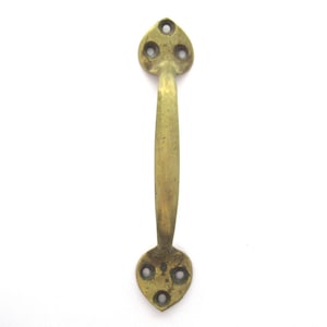 May include: A brass door handle with a curved shape and a heart-shaped design at each end. The handle has three holes for mounting.