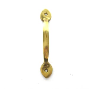 May include: A gold-toned metal door handle with a curved shape and rounded ends. The handle has a single hole for mounting.