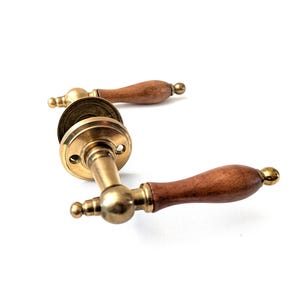 May include: A gold door handle with a wooden lever. The handle has a round base and a decorative knob on the end of the lever.