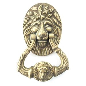 Pode incluir: Um batente de porta de cabeça de leão dourado com um design de corda na alça.