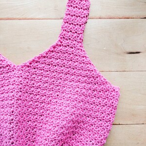 Peut inclure: Un d&eacute;bardeur en crochet rose avec un col rond et des bretelles fines.