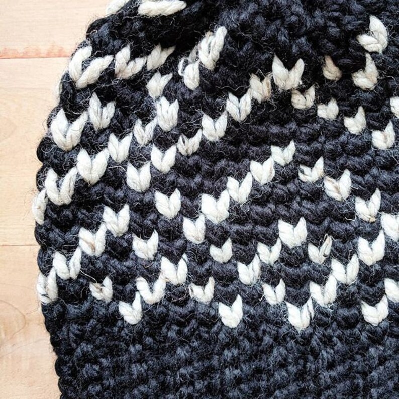 May include: Close-up of a black and white crocheted hat with a chevron pattern.