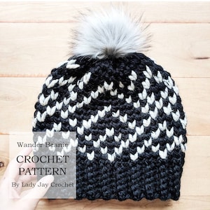 May include: Black and white crochet beanie with a white pom pom. The beanie has a chevron pattern. The text "Wander Beanie CROCHET PATTERN By Lady Jay Crochet" is on the image.