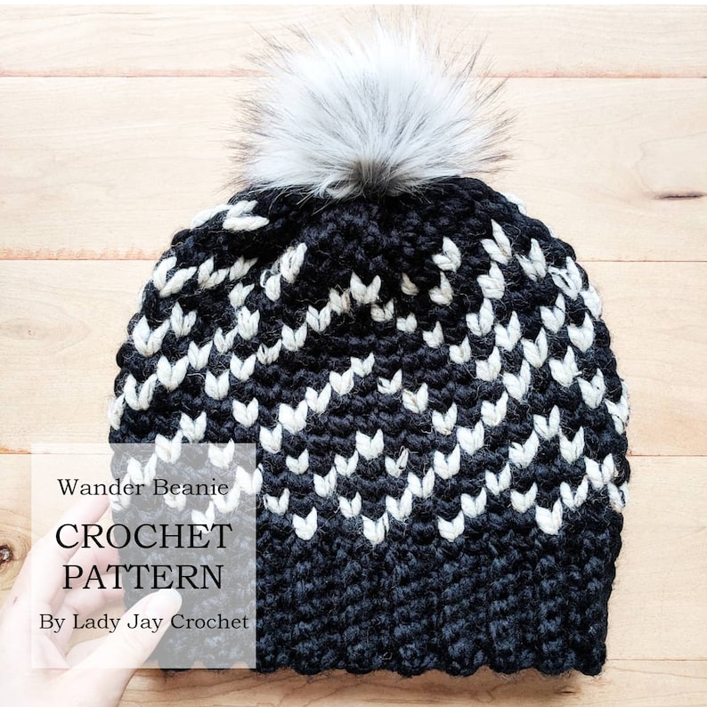 May include: Black and white crochet beanie with a white pom pom. The beanie has a chevron pattern. The text "Wander Beanie CROCHET PATTERN By Lady Jay Crochet" is on the image.