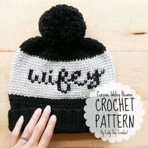 Peut inclure: Un bonnet en crochet noir et blanc avec le mot "wifey" en cursive sur le devant. Le bonnet a un pompon noir sur le dessus et une bande noire autour du bas. Le bonnet est sur une surface en bois. Bonnet Wifey en cursive PATRON DE CROCHET Par Lady Jay Crochet