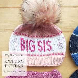 Puede incluir: Gorro de punto rosa y blanco con un pompón rosa y las palabras "Big Sis" bordadas en rosa.