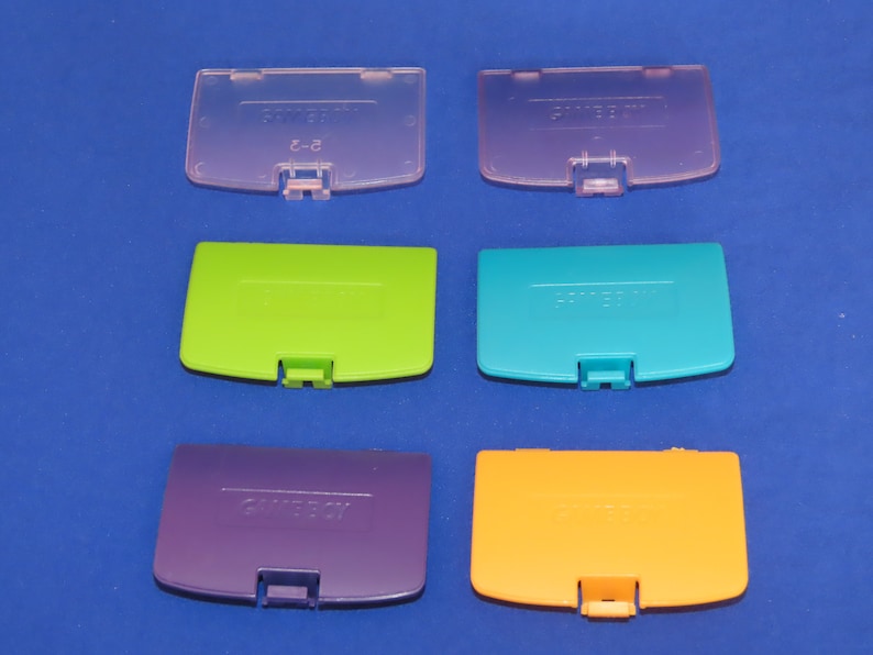 May include: Six different coloured Game Boy Color game cartridge covers. The covers are translucent and have the Game Boy Color logo printed on them. The colours are pink, green, blue, purple, and orange.
