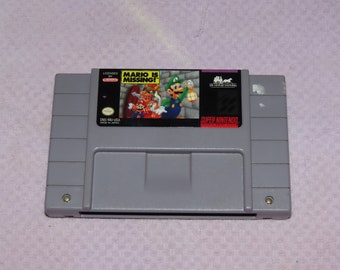 May include: A Super Nintendo Entertainment System (SNES) game cartridge for the game "Mario is Missing!"  The cartridge is gray with a label featuring a colorful image of Mario, Luigi, and Toad. The label also includes the text "Licensed by Nintendo" and "Super Nintendo Entertainment System".
