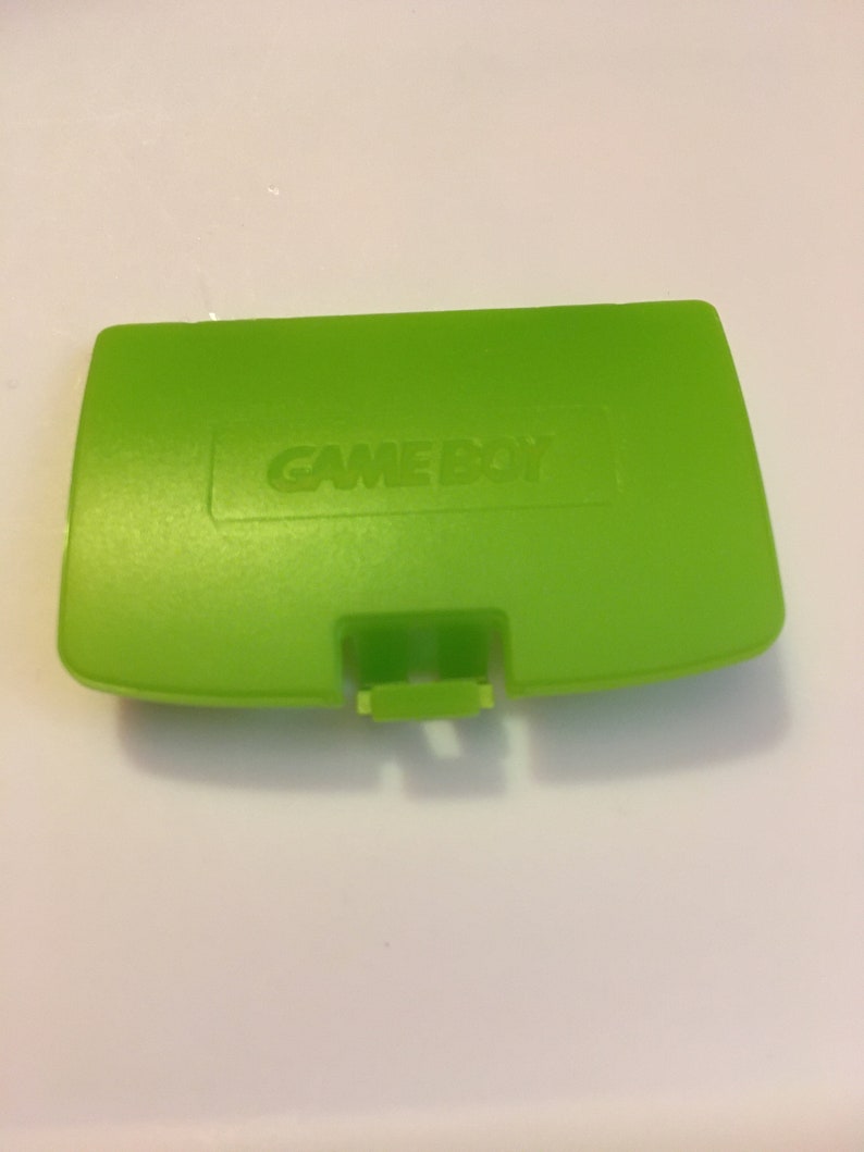 May include: A bright green Game Boy Color game cartridge case with the words "GAME BOY" embossed on the top.