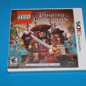 May include: A white Nintendo 3DS game case with a colorful image of Lego characters from the Disney Pirates of the Caribbean video game. The case features the game title "LEGO Pirates of the Caribbean: The Video Game" and the Nintendo 3DS logo.