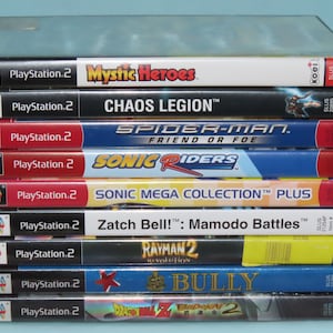 May include: A stack of ten PlayStation 2 video game cases. The games include Mystic Heroes, Chaos Legion, Spider-Man: Friend or Foe, Sonic Riders, Sonic Mega Collection Plus, Zatch Bell!: Mamodo Battles, Rayman 2: Revolution, Bully, and Dragon Ball Z: Budokai 2.