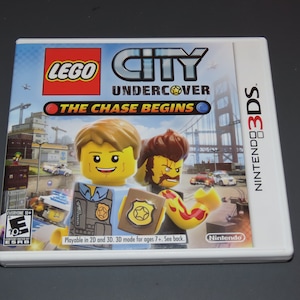 May include: A white Nintendo 3DS game case with a colorful image of Lego City Undercover: The Chase Begins. The game features two Lego minifigures, one in a police uniform and the other with a red and yellow flame design. The game is rated E for Everyone 10+ by the ESRB.